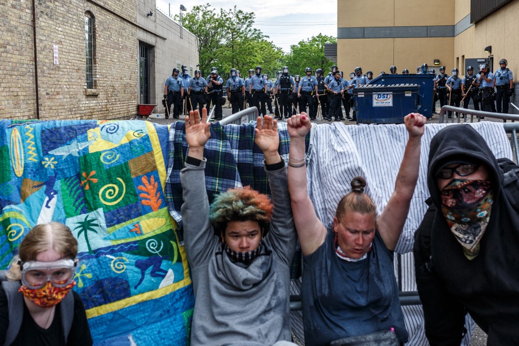 Protestors hold their hands up as they cry from from tear gas during a demonstration in a call for justice for George Floyd following his death, outside the 3rd Police Precinct on May 27, 2020 in Minneapolis, Minnesota. - The family of an African American man killed by Minneapolis police while handcuffed in custody demanded Wednesday that the officers be charged with murder. After a night of angry protests over the death of George Floyd, with law enforcement firing tear gas and rubber bullets in the northern US city, his sister Bridgett Floyd demanded the arrest of the four white police officers involved in his death. (Photo by Kerem Yucel / AFP)