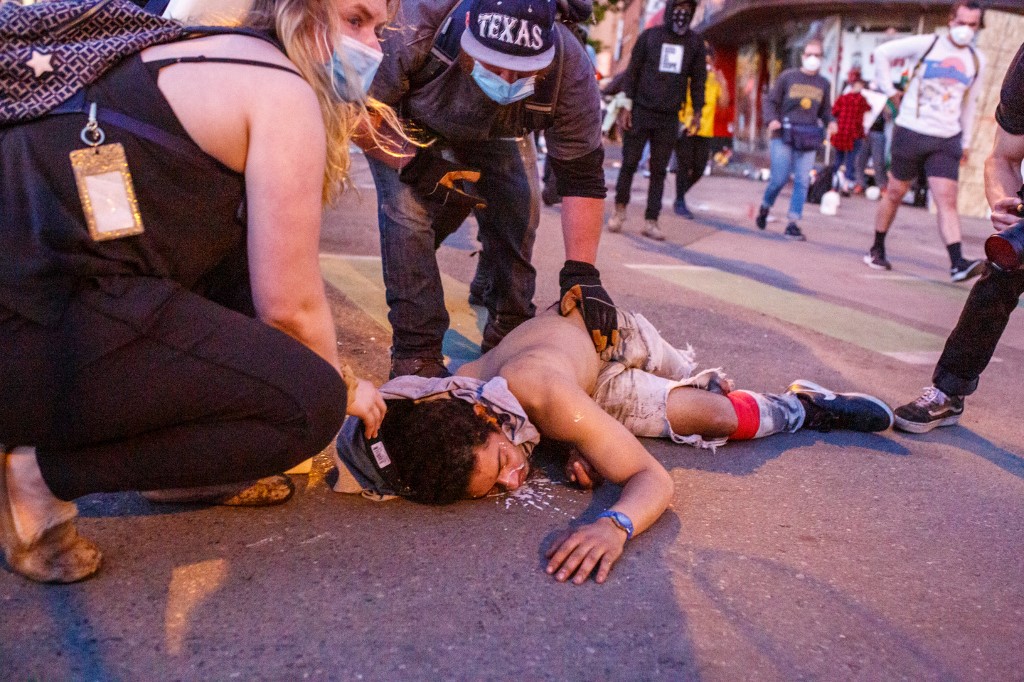People assist an injured man during a protest outside the Third Police Precinct on May 28, 2020 in Minneapolis, Minnesota, over the death of  George Floyd, an unarmed black man, who died after a police officer kneeled on his neck for several minutes. - Authorities in Minneapolis and its sister city St. Paul got reinforcements from the National Guard on May 28 as they girded for fresh protests and violence over the shocking police killing of a handcuffed black man. Three days after a policeman was filmed holding his knee to George Floyd's neck for more than five minutes until he went limp, outrage continued to spread over the latest example of police mistreatment of African Americans. (Photo by Kerem Yucel / AFP)