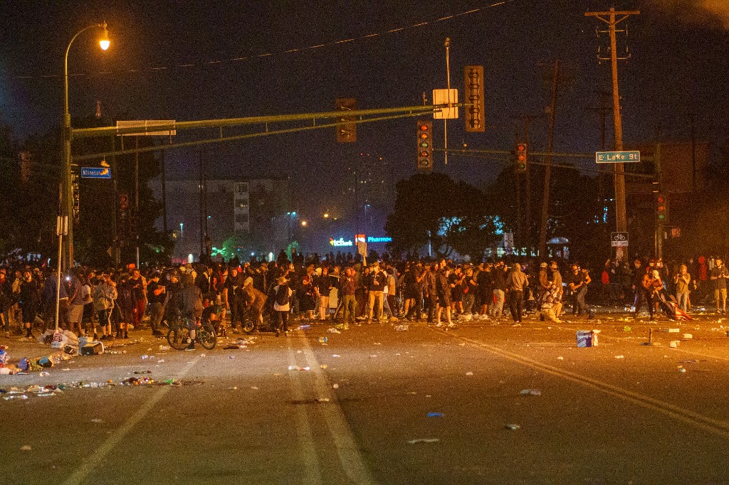 Protesters gather in the streeet near the Third Police Precinct on May 28, 2020 in Minneapolis, Minnesota, during a protest over the death of George Floyd, an unarmed black man, who died after a police officer kneeled on his neck for several minutes. - A police precinct in Minnesota went up in flames late on May 28 in a third day of demonstrations as the so-called Twin Cities of Minneapolis and St. Paul seethed over the shocking police killing of a handcuffed black man. The precinct, which police had abandoned, burned after a group of protesters pushed through barriers around the building, breaking windows and chanting slogans. A much larger crowd demonstrated as the building went up in flames. (Photo by kerem yucel / AFP)