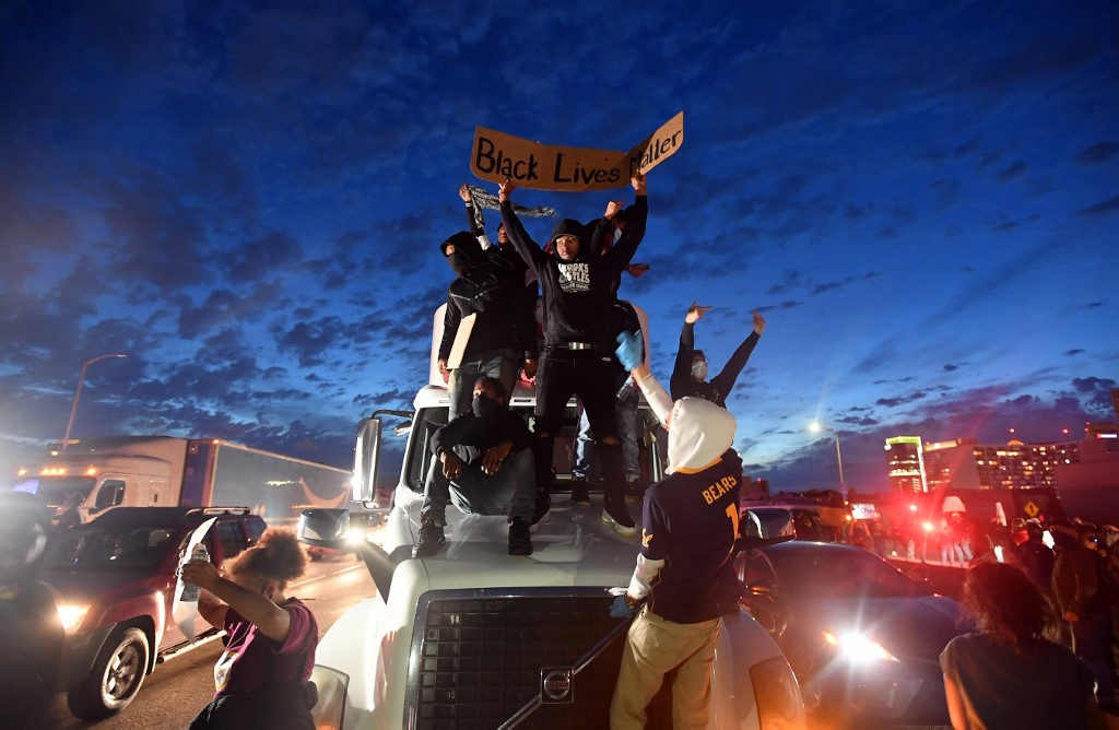 Protesters jump onto a semi truck while blocking traffic on Interstate 580 during a demonstration over the death of George Floyd, a black man who died after a white policeman kneeled on his neck for several minutes, in Oakland California, on May 29, 2020. - Protesters shouted and threw objects at police who fired back with rubber bullets, flash bangs and chemical agents to disperse crowds. (Photo by Josh Edelson / AFP)
