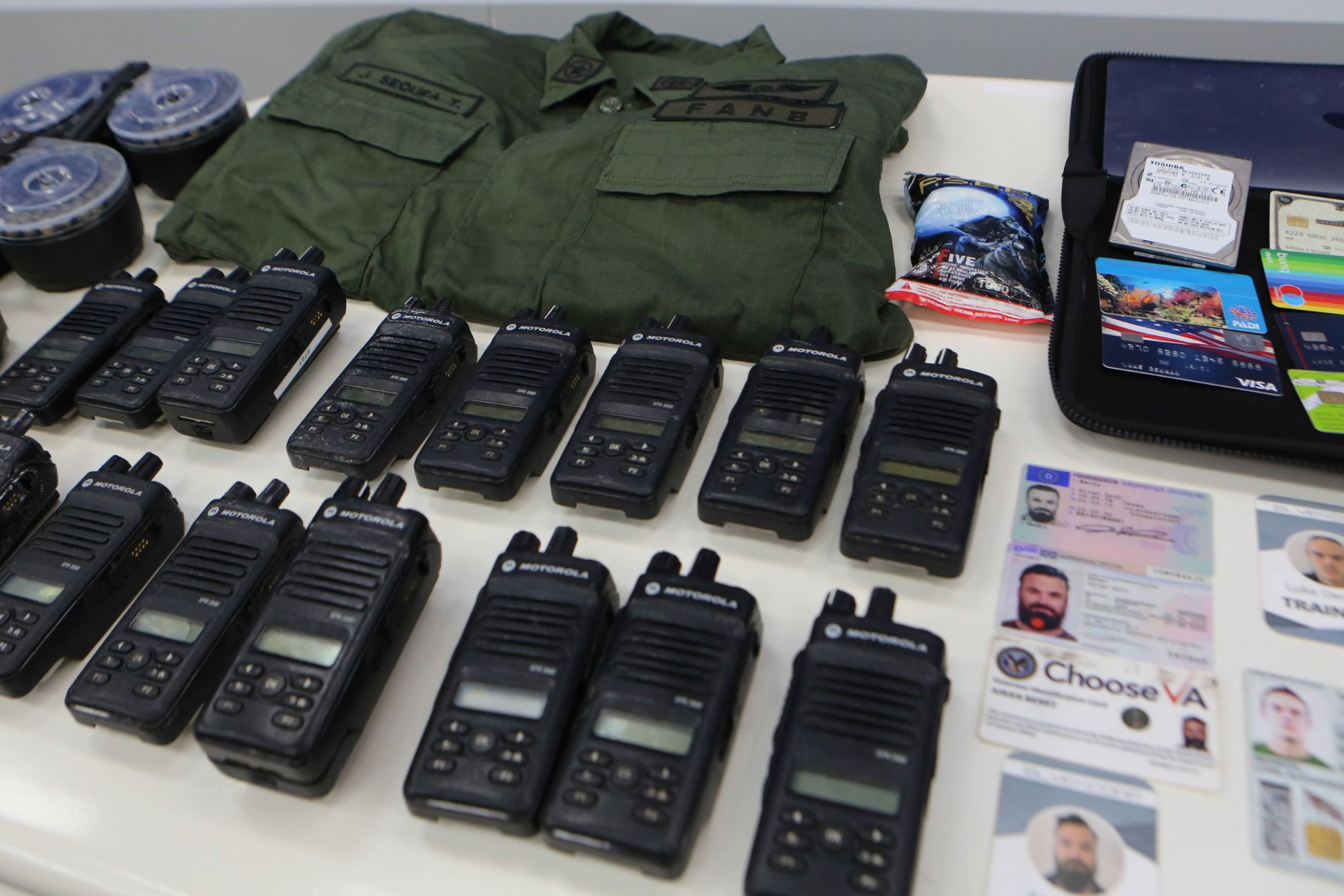 Handout picture released by the Venezuelan Presidency showing identification cards, two-way radios and other military gear allegedly seized to US citizens arrested by security forces during a meeting with members of the Bolivarian National Armed Forces (FANB), at Miraflores Presidential Palace in Caracas on May 4, 2020. - Venezuela is to try two Americans, identified as Luke Denman and Airan Berry, allegedly captured during a failed sea attack by mercenaries, President Nicolas Maduro said on May 6. (Photo by Marcelo Garcia / Venezuelan Presidency / AFP) / RESTRICTED TO EDITORIAL USE - MANDATORY CREDIT 