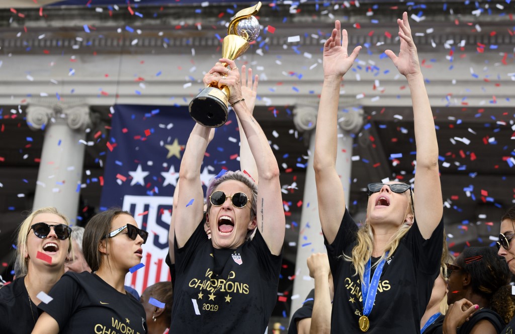 USA women's soccer player Lindsey Horan(L)Megan Rapinoe (C), Alexandra Long(R) and other team members celebrate with the trophy in front of the City Hall after the ticker tape parade for the women's World Cup champions on July 10, 2019 in New York. - Tens of thousands of fans are poised to pack the streets of New York on Wednesday to salute the World Cup-winning US women's team in a ticker-tape parade. Four years after roaring fans lined the route of Lower Manhattan's fabled 