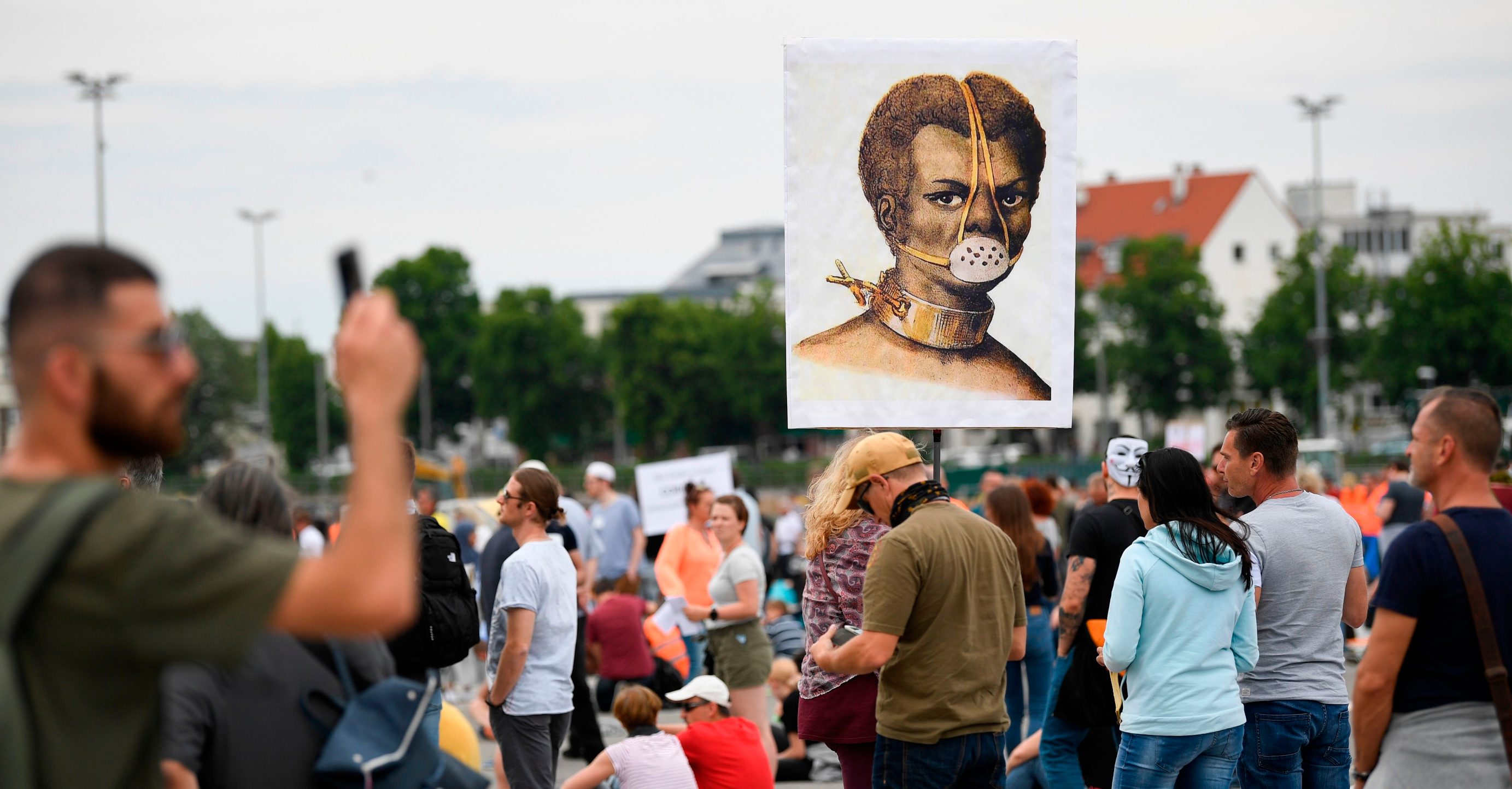 Demonstrators hold a placard showing a slave with a mask during a demonstration against the restrictions implemented to limit the spread of the novel coronavirus, at the grounds of the Cannstatter Wasen festival in Stuttgart, southern Germany, on May 9, 2020. - Several thousand people are expected to take part in the demonstration, attracting left and right-wing extremists, as well as conspiracy theorists and anti-vaxxers, who argue that the restrictions are an illegal attempt to curtail civil liberties by an authoritarian state. The event is organised by the 