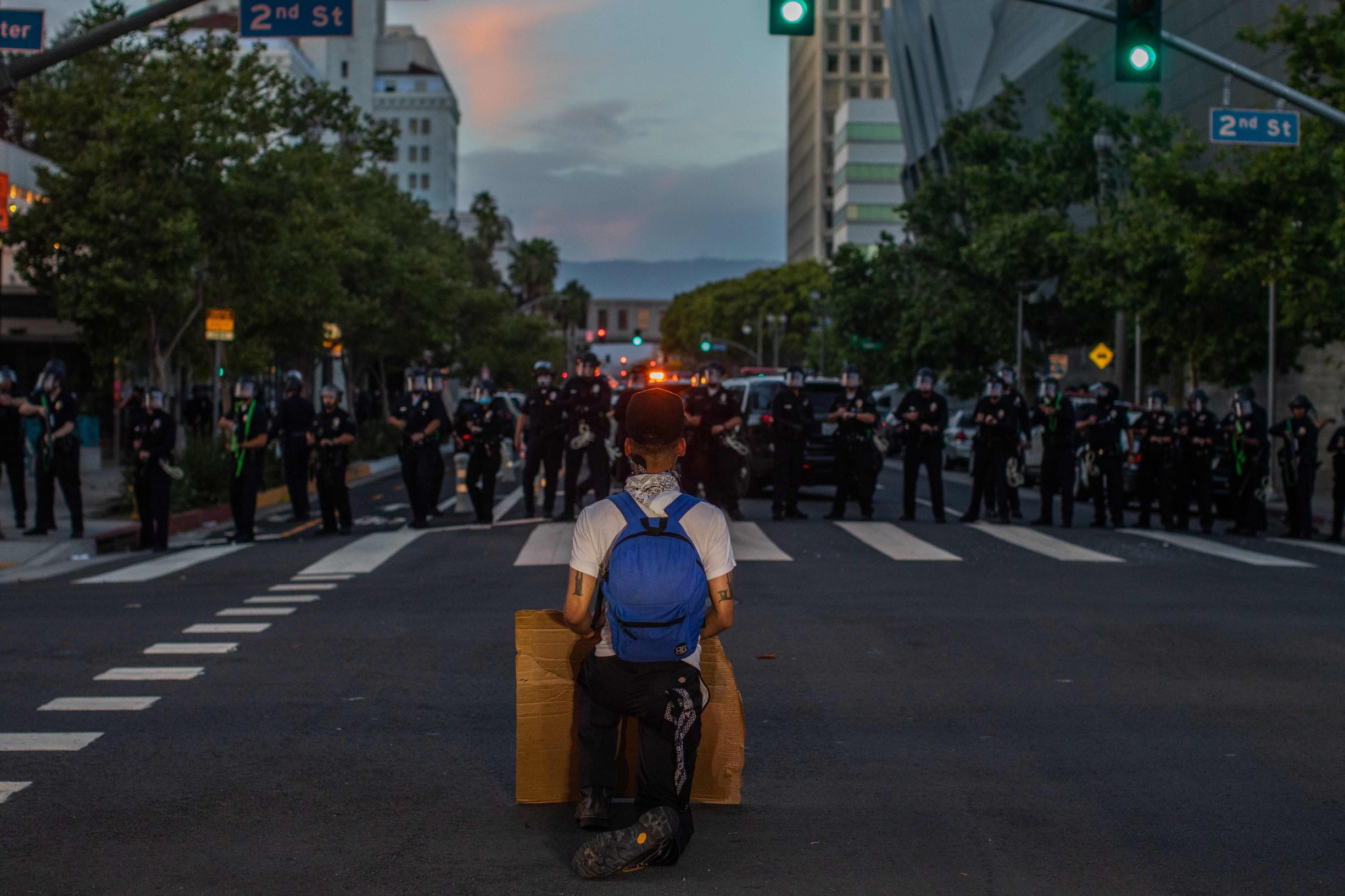A demonstrator kneels in front of a Police line in Downtown Los Angeles on May 30, 2020 during a protest against the death of George Floyd, an unarmed black man who died while while being arrested and pinned to the ground by the knee of a Minneapolis police officer. - Clashes broke out and major cities imposed curfews as America began another night of unrest Saturday with angry demonstrators ignoring warnings from President Donald Trump that his government would stop violent protests over police brutality 
