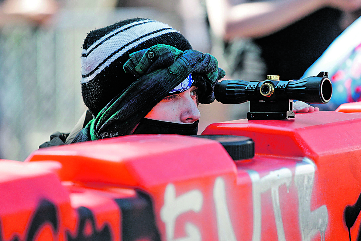 A protester uses a scope on top of a barricade to look for police approaching the newly created Capitol Hill Autonomous Zone (CHAZ) in Seattle, Washington on June 11, 2020. - The area surrounding the East Precinct building has come to be known as the CHAZ, Capitol Hill Autonomous Zone. Volunteer medics are available to tend to medical needs, alongside tents with medical supplies, gourmet food donated form local restaurants, fruit, snacks, water bottles free for whomever needed them. (Photo by Jason Redmond / AFP)