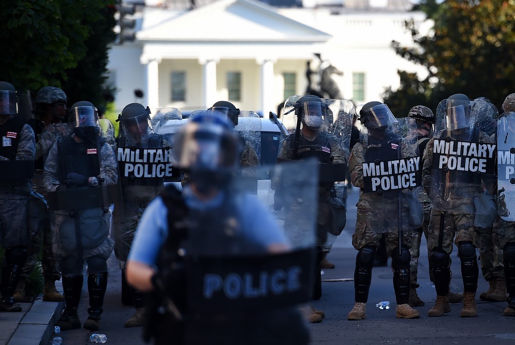 Military Police members hold a perimeter near the White House as demonstrators gather to protest the killing of George Floyd on June 1, 2020 in Washington, DC. - Police fired tear gas outside the White House late Sunday as anti-racism protestors again took to the streets to voice fury at police brutality, and major US cities were put under curfew to suppress rioting.With the Trump administration branding instigators of six nights of rioting as domestic terrorists, there were more confrontations between protestors and police and fresh outbreaks of looting. Local US leaders appealed to citizens to give constructive outlet to their rage over the death of an unarmed black man in Minneapolis, while night-time curfews were imposed in cities including Washington, Los Angeles and Houston. (Photo by Olivier DOULIERY / AFP)