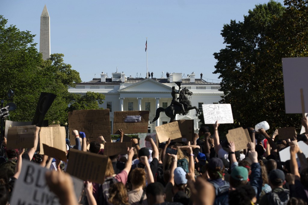 Demonstrators hold up placards protest outside of the White House, over the death of George Floyd in Washington D.C. on June 1, 2020. - President Donald Trump vowed Monday to order a military crackdown on once-in-a-generation violent protests gripping the United States, saying he was sending thousands of troops onto the streets of the capital and threatening to deploy soldiers to states unable to regain control. (Photo by Jose Luis Magana / AFP)