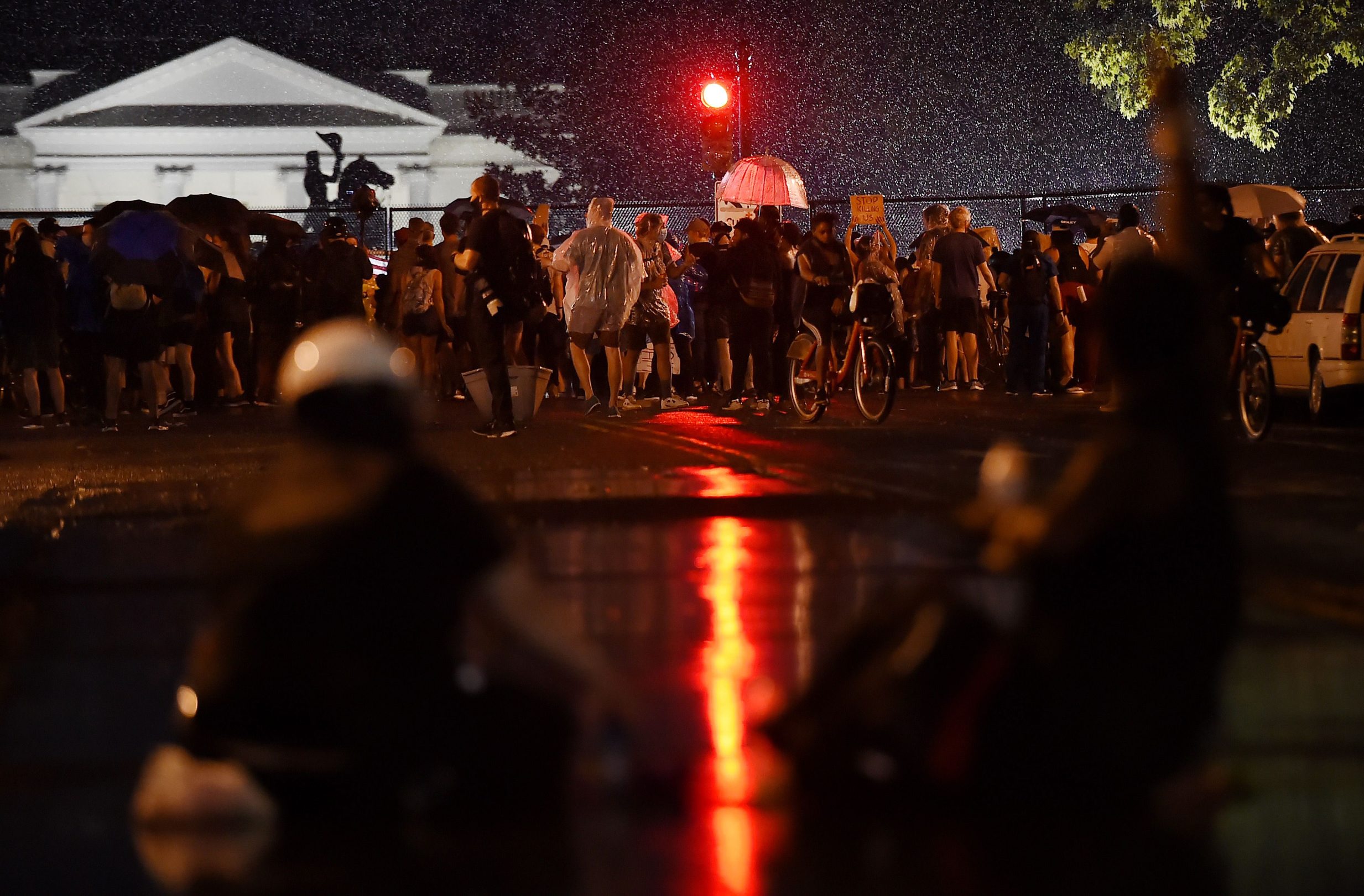 Protesters stand in the rain in front of Lafayette park near the White House to protest the death of George Floyd, who died in police custody in Minneapolis on June 4, 2020 in Washington, DC. - On May 25, 2020, Floyd, a 46-year-old black man suspected of passing a counterfeit  bill, died in Minneapolis after Derek Chauvin, a white police officer, pressed his knee to Floyd's neck for almost nine minutes. (Photo by Olivier DOULIERY / AFP)