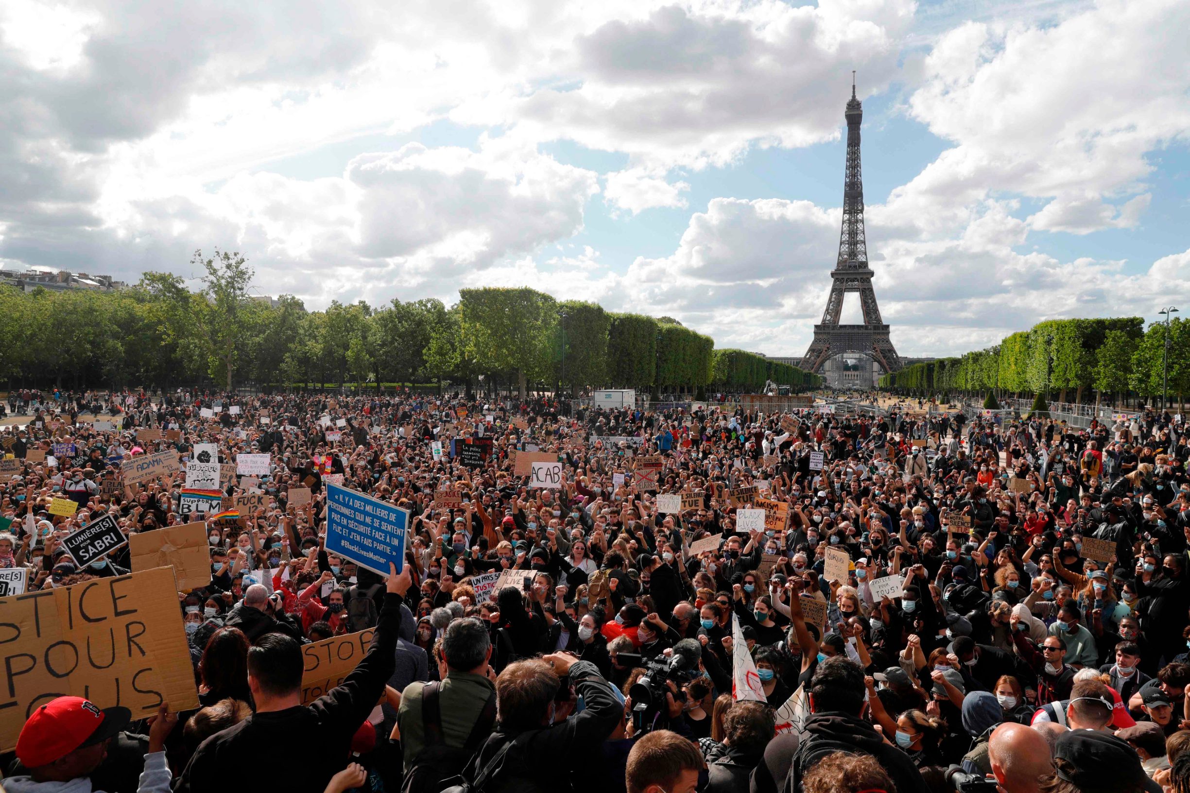 People gather on Champs de Mars in front of Eiffel Tower, in Paris on June 6, 2020, as part of 'Black Lives Matter' worldwide protests against racism and police brutality in the wake of the death of George Floyd, an unarmed black man killed while apprehended by police in Minneapolis, US. - Police banned the rally as well as a similar second one on the Champs de Mars park facing the Eiffel Tower today, saying the events were organised via social networks without official notice or consultation. But on June 2, another banned rally in Paris drew more than 20000 people in support of the family of Adama Traore, a young black man who died in police custody in 2016. (Photo by GEOFFROY VAN DER HASSELT / AFP)