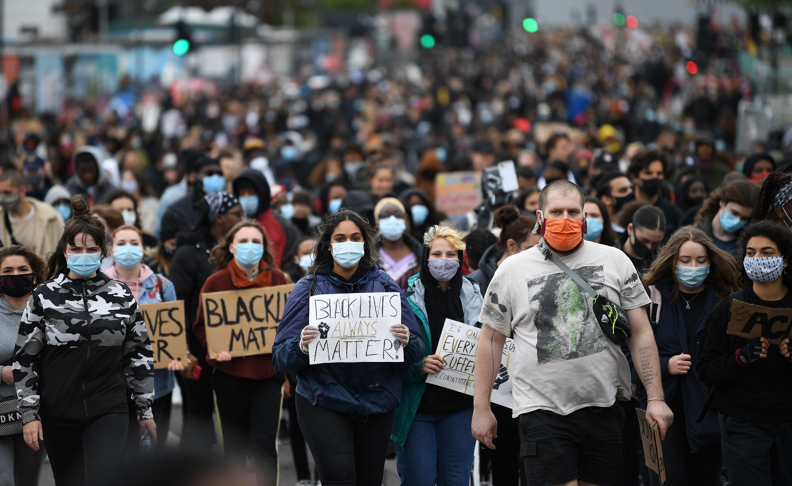 Demonstrators, some wearing PPE (personal protective equipment), including a face mask as a precautionary measure against COVID-19,  hold placards as they attend a protest march to the US Embassy in London on June 6, 2020, to show solidarity with the Black Lives Matter movement in the wake of the killing of George Floyd, an unarmed black man who died after a police officer knelt on his neck in Minneapolis. - The United States braced Friday for massive weekend protests against racism and police brutality, as outrage soared over the latest law enforcement abuses against demonstrators that were caught on camera. With protests over last week's police killing of George Floyd, an unarmed black man, surging into a second weekend, President Donald Trump sparked fresh controversy by saying it was a 