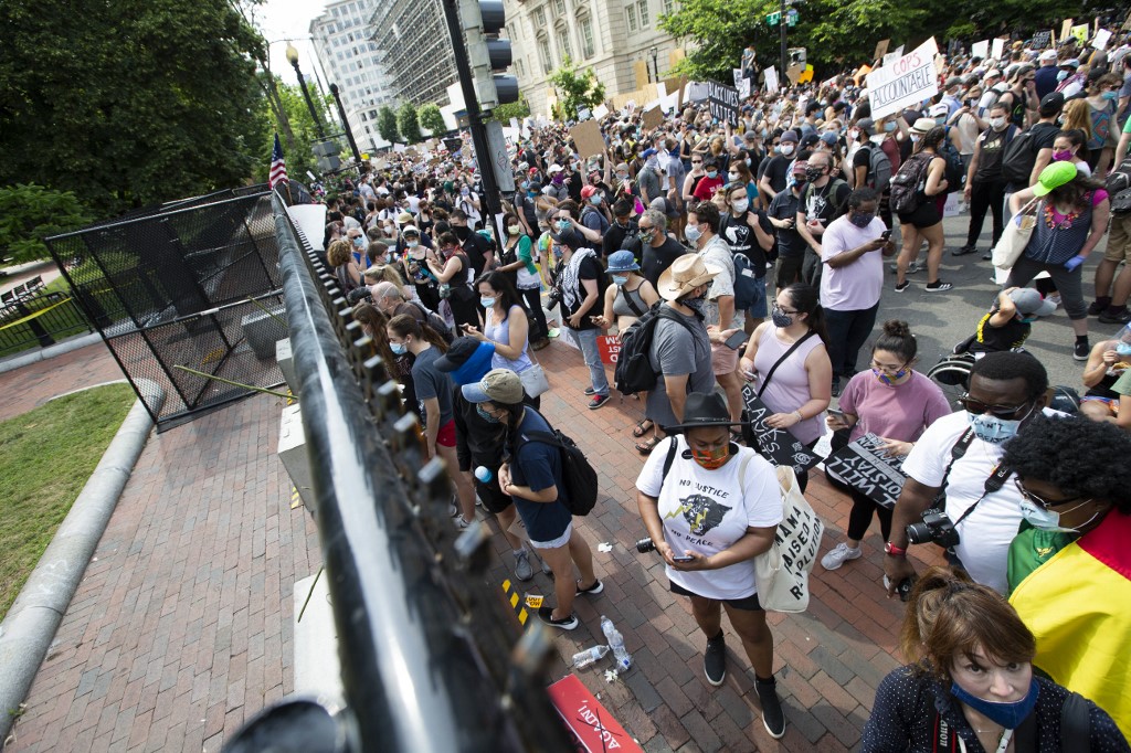 Demonstrators hold up their signs as they march North Lafayette Square with as fence dividing during a peaceful protest against police brutality and racism, June 6, 2020 in Washington D.C. - Demonstrations are being held across the US following the death of George Floyd on May 25, 2020, while being arrested in Minneapolis, Minnesota. (Photo by Jose Luis Magana / AFP)