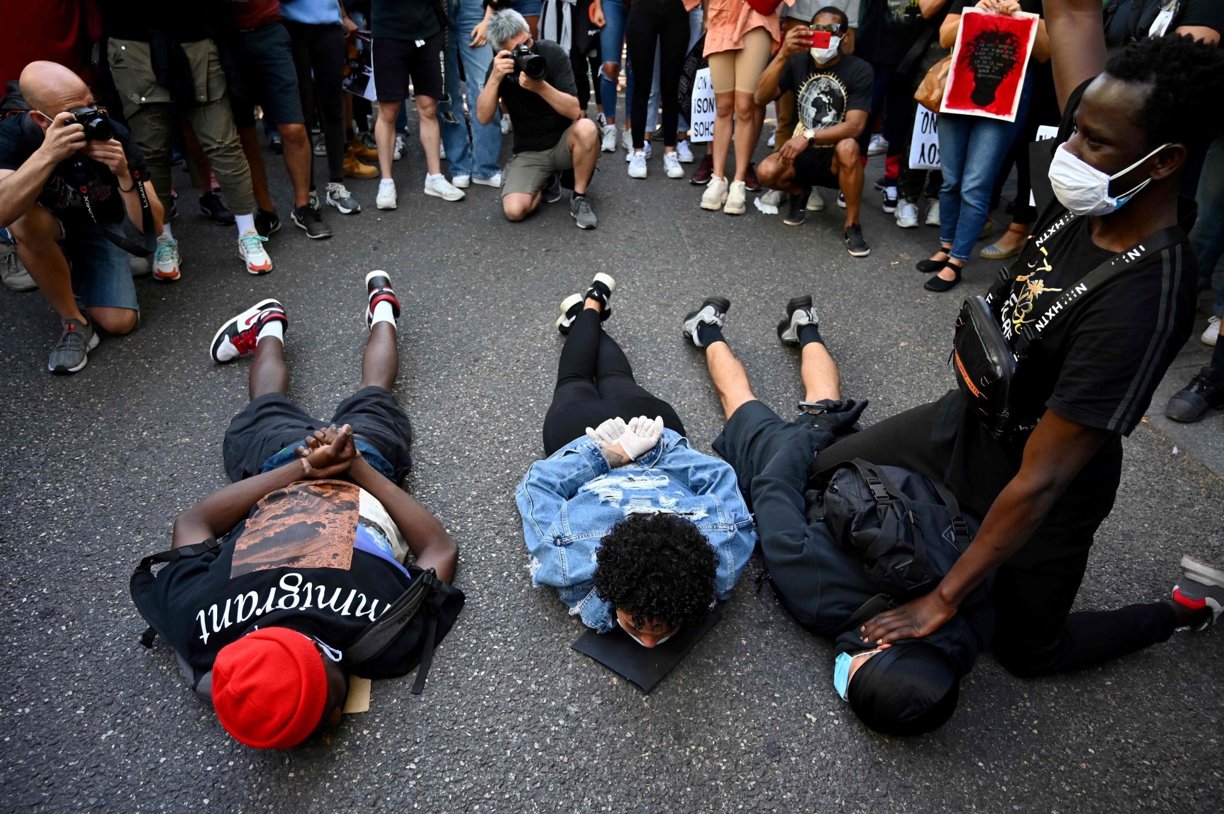 Protesters re-enact the event leading to the death of George Floyd, an unarmed black man who died after a white policeman knelt on his neck during an arrest in the US, in Madrid, on June 7, 2020 during a demonstration against racism and in solidarity with the Black Lives Matter movement. (Photo by Gabriel BOUYS / AFP)