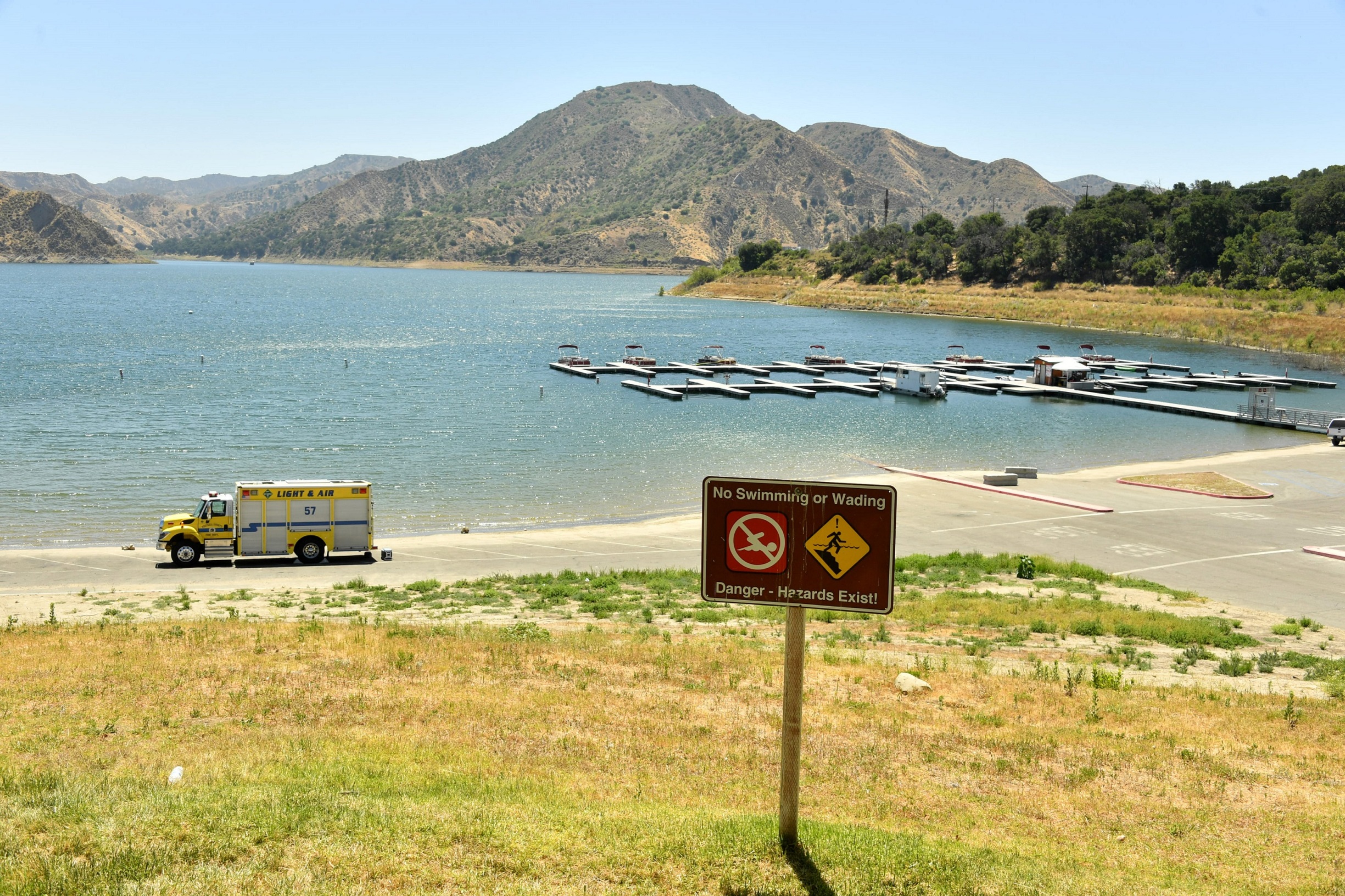 PIRU, CALIFORNIA - JULY 09:  An emergency response vehicle sits in a parking lot near a danger sign warning visitor of hazards for swimming and wading at Lake Piru, where actress Naya Rivera was reported missing Wednesday, on July 9, 2020 in Piru, California.  Rivera, known for her role in 