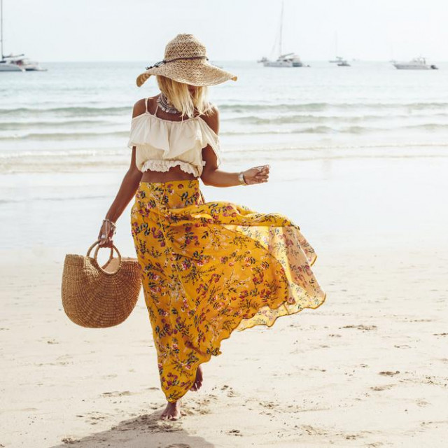 Girl wearing floral maxi skirt walking barefoot on the sea shore, Thailand, Phuket. Bohemian clothing style.