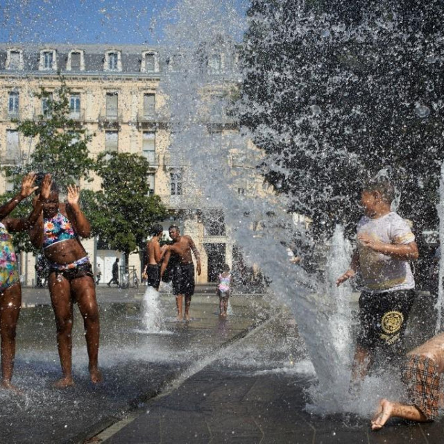 Djeca i prolaznici se rashlađuju na gradskoj fontani u Toulouseu.