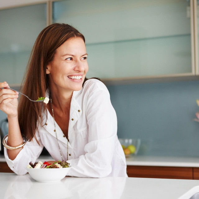 Woman having healthy breakfast and looking away with smile