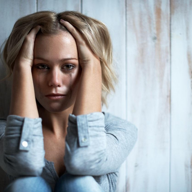 Portrait of a tearful young woman with her hand in her hair