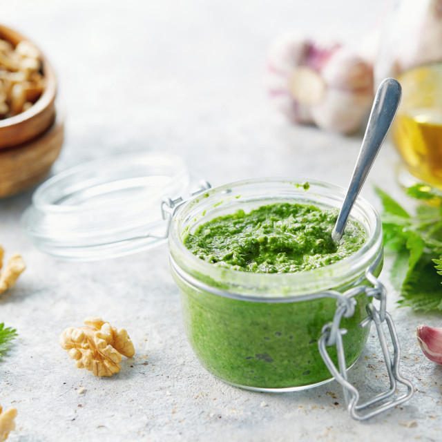 Vegetarian nettle, garlic and walnut pesto. Close up of jar of homemade nettle pesto with walnuts and garlic.