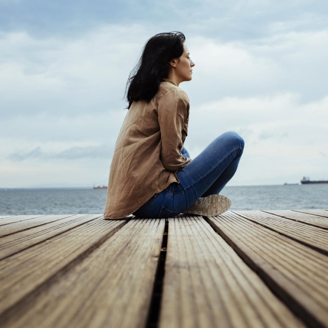 Young brunette sitting on the seaside boardwalk