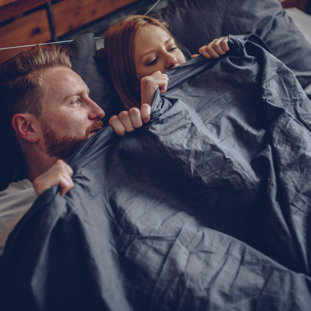 Two people, young heterosexual couple relaxing in bed, in the morning.