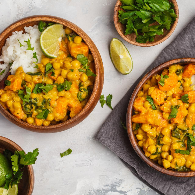 Vegan Sweet Potato Chickpea curry in wooden bowl on a light background, top view, food flat lay. Healthy vegetarian food concept.