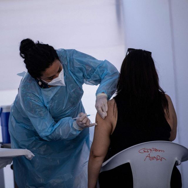 A health worker administers a dose of the Chinese CoronaVac vaccine against COVID-19 to a woman at a vaccination centre in Santiago, on March 24, 2021. - Chilean authorities have been implementing, among other measures, a selective quarantine in areas with a high incidence of infection and have placed an emphasis on controlling the pandemic by mass screening. (Photo by MARTIN BERNETTI/AFP)