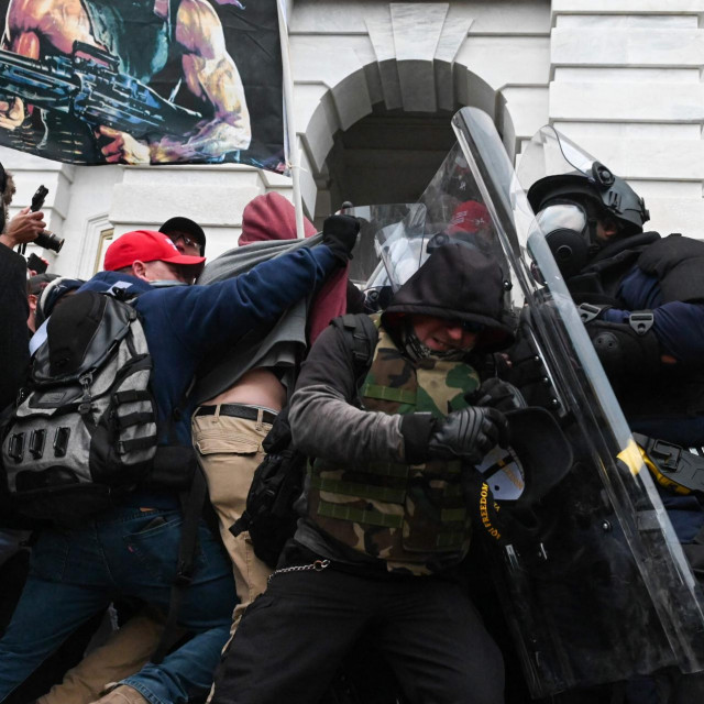 (FILES) In this file photo riot police push back a crowd of supporters of US President Donald Trump after they stormed the Capitol building on January 6, 2021 in Washington, DC. - Two Capitol Police officers sued former US president Donald Trump on March 30, 2021 for inciting the January 6 insurrection that left dozens of their fellow officers injured and one dead. Officers James Blassingame and Sidney Hemby said they suffered ”physical and emotional injuries” in the riot they said was fomented by Trump, when he was in his final weeks as president and refusing to accept his election defeat. (Photo by ROBERTO SCHMIDT/AFP)