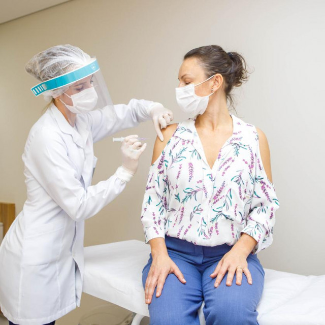 nurse applying vaccine to woman