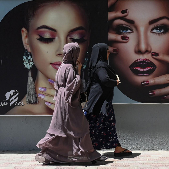 Žene u burkama prolaze pored reklame za kozmetički salon u Kabulu