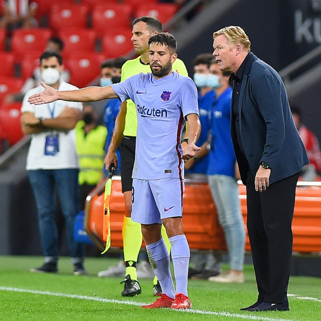 Barcelona's Dutch coach Ronald Koeman (R) speaks with Barcelona's Spanish defender Jordi Alba during the Spanish League football match between Athletic Club Bilbao and FC Barcelona at the San Mames stadium in Bilbao on August 21, 2021. (Photo by ANDER GILLENEA/AFP)