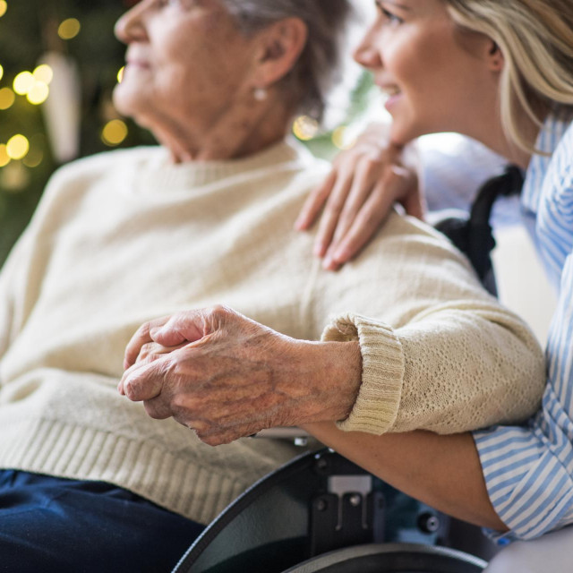 &lt;p&gt;A senior woman in wheelchair with a health visitor at home at Christmas time.&lt;/p&gt;

