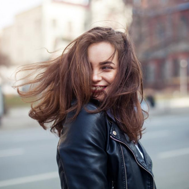 &lt;p&gt;Young beautiful model girl smiles and looks back in the city. Dynamically young girl walks down the street.Hair fluttering in the wind.&lt;/p&gt;