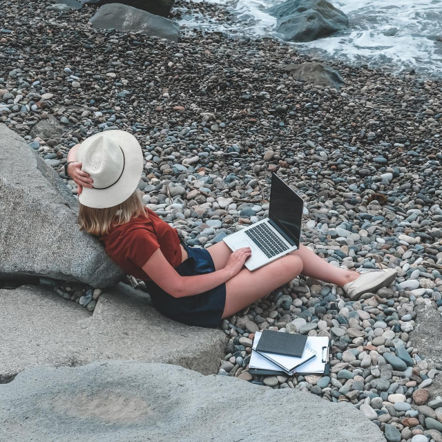 Remote work.Girl freelancer works remotely on the seashore.workation, remote work,WFVH,Van Life vibes work from vacation home,work travel,remotely work.Travelling