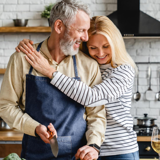 &lt;p&gt;Beautiful mature couple hugging while cooking vegetable salad at kitchen table&lt;/p&gt;