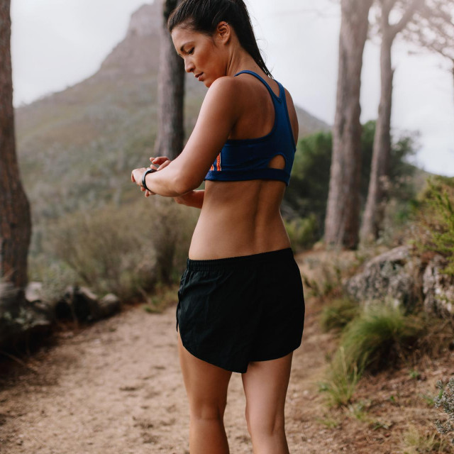 &lt;p&gt;Female runner checking fitness progress on her smart watch. Asian woman using fitness app to monitor workout performance, while walking through mountain trail.&lt;/p&gt;