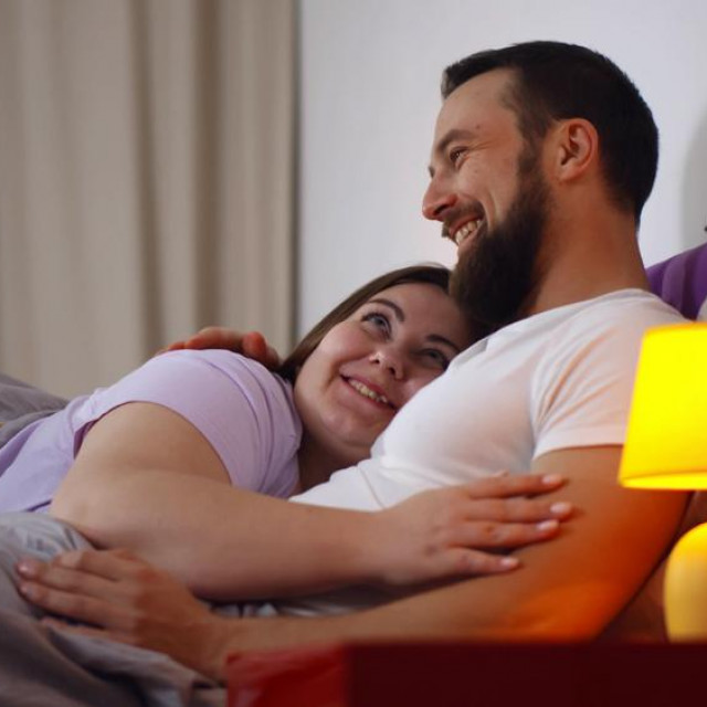 &lt;p&gt;Happy young couple hugging in bed and communicating. Side view of overweight girlfriend and bearded boyfriend embracing and relaxing n bedroom together at home&lt;/p&gt;