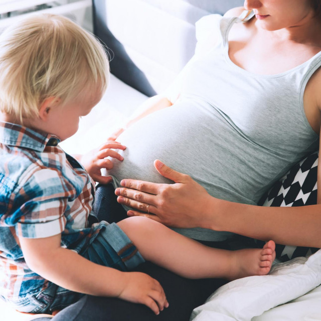 &lt;p&gt;Pregnant mother and son are talking and spending time together at home. Little child boy looking at her mother pregnant tummy. Pregnancy, family, parenthood, preparation and expectation concepts.&lt;/p&gt;