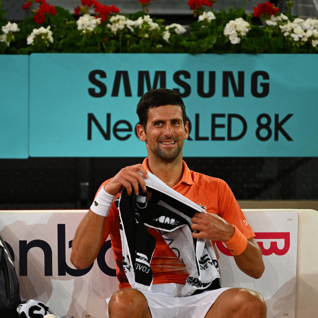 Serbia‘s Novak Djokovic smiles on the bench during the 2022 ATP Tour Madrid Open tennis tournament singles match against France‘s Gael Monfils at the Caja Magica in Madrid on May 3, 2022. (Photo by GABRIEL BOUYS/AFP)