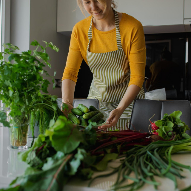 &lt;p&gt;Blond woman in apron cooking healthy fresh vegetable salad in the home kitchen. Female holding cucumber plate or bowl for washing. Organic farming dish for loosing weight in summer. Learning to cook&lt;/p&gt;