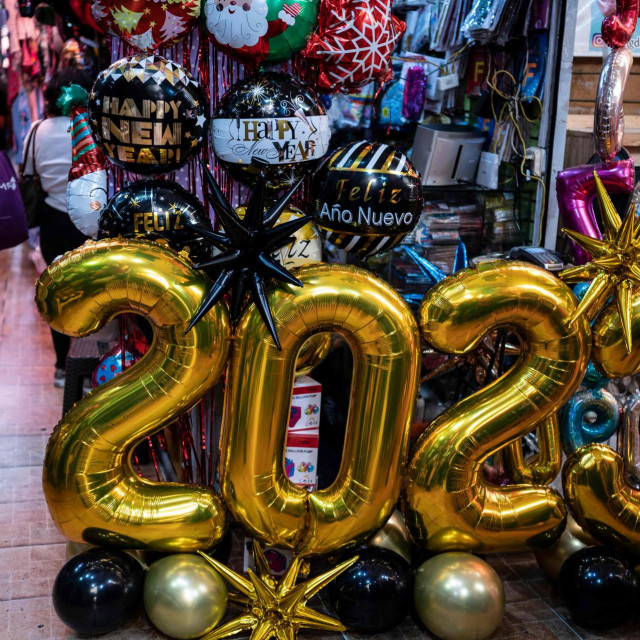 &lt;p&gt;A woman uses her cell phone as she walks past balloons and 2023 signs while shopping at the San Jacinto market in the historic center of Caracas on December 30, 2022, on the eve of the end-of-the-year celebrations. (Photo by Yuri CORTEZ/AFP)&lt;/p&gt;