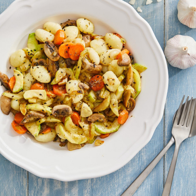 &lt;p&gt;Tasty homemade vegan gnocchi with fresh vegetables. carrot, zucchini, mushrooms and olive oil, served on a modern ceramic plate, with seasoning and herbs on a blue rustic wooden kitchen or restaurant table, representing a healthy lifestyle, wellbeing and body care, top view with a copy space&lt;/p&gt;