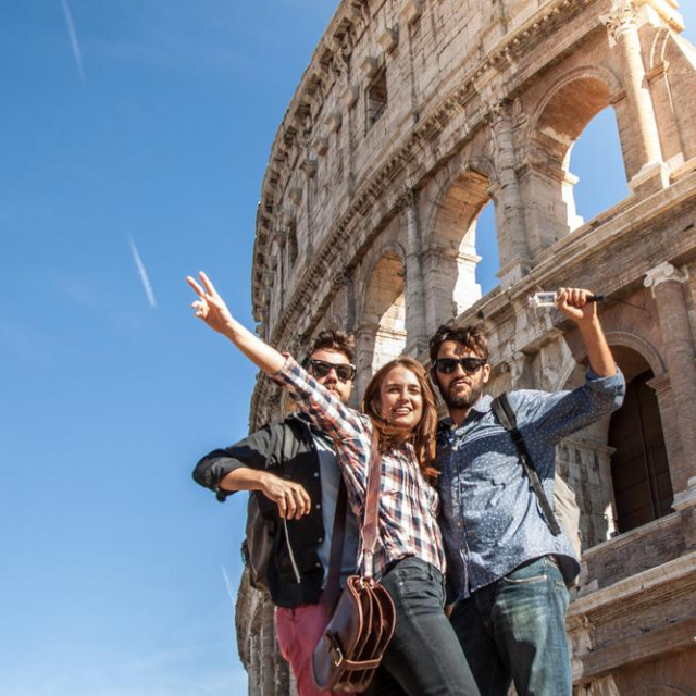 &lt;p&gt;Three young friends tourists posing for funny pictures in front of colosseum in rome. Blue sky and lens flare on sunny day.&lt;/p&gt;