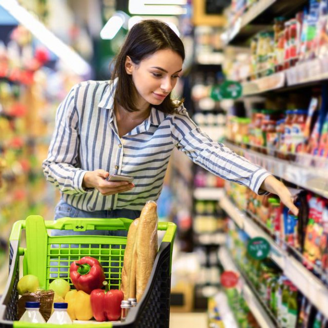 &lt;p&gt;Portrait Of Millennial Lady Holding And Using Smartphone Buying Food Groceries Walking In Supermarket With Trolley Cart. Female Customer Shopping With Checklist, Taking Products From Shelf At The Shop&lt;/p&gt;