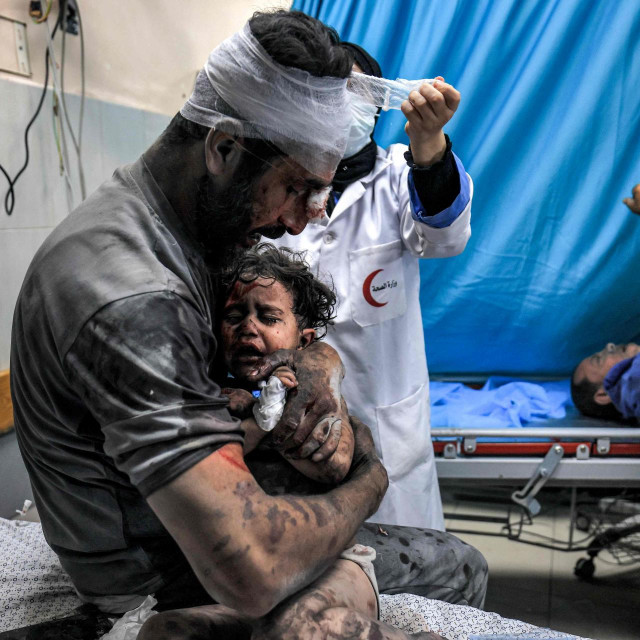 Ozlijeđeni muškarac drži ozlijeđeno dijete u bolnici u Gazi