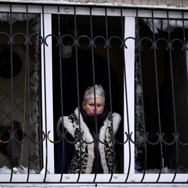 Žena gleda kroz prozor razorene zgrade u Kijevu
