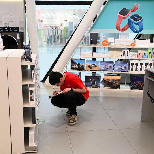 A worker is seen in a Xiaomi store at a shopping mall in Beijing on March 19, 2024. (Photo by Pedro PARDO/AFP)