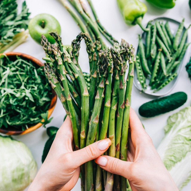 Woman hands folding bunch of fresh asparagus, healthy nutrition concept.
