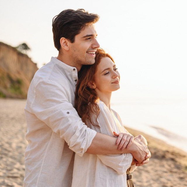 Close up profile happy satisfied smiling young couple two friends family man woman 20s in white clothes hug rest together at sunrise over sea beach ocean outdoor seaside in summer day sunset evening.
