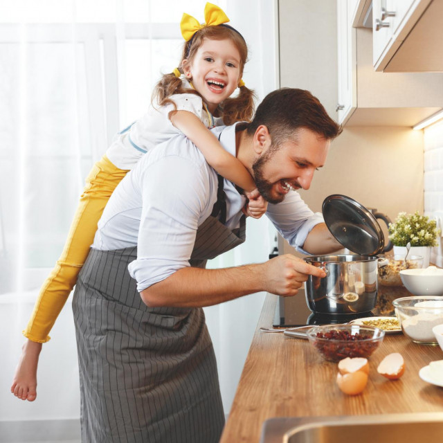 happy family in kitchen. Father and child daughter knead dough and bake the biscuits together