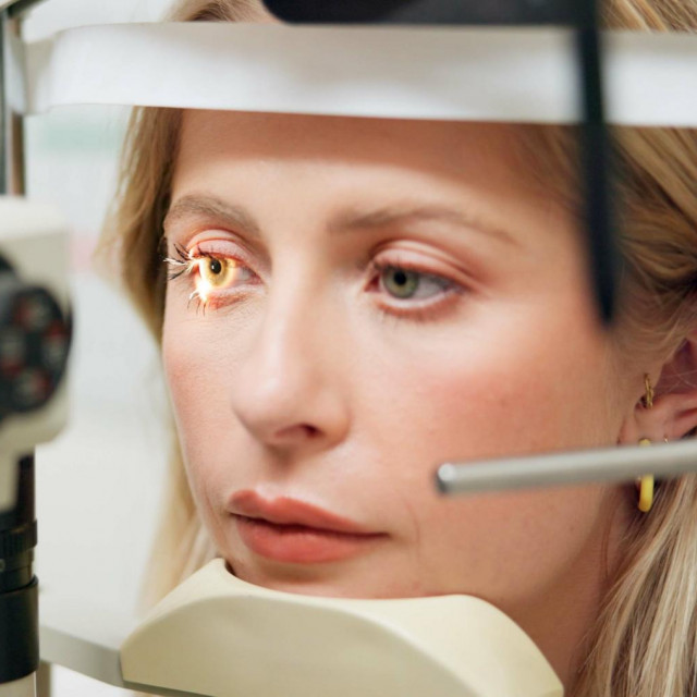 Woman, optometry and slit lamp for vision, test and care in wellness assessment with health at clinic. Doctor, optician and patient by machine, light and laser for retina scan with lens for eye exam